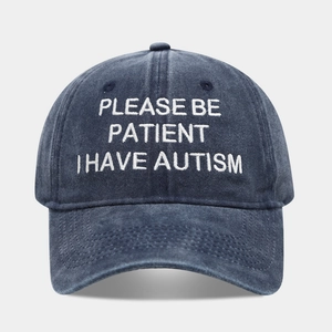 Detail of navy washed cotton baseball cap with white Please Be Patient embroidery