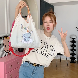 Detail of cute elephant embroidery on white canvas tote bag with red braided strap