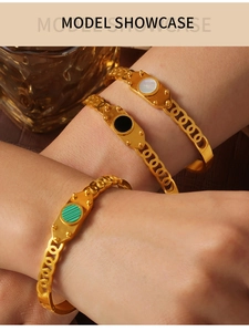 Three stacked gold titanium bracelets featuring white, black, and green inlay accents