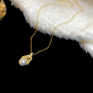 Detail einer 18k vergoldeten Halskette mit Zirkon und Perle auf weichem Plüschstoff