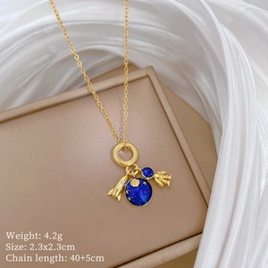 Detail of gold necklace with astronaut, rocket and blue planet pendants on beige silk