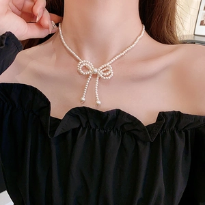 Close-up of elegant bow-shaped pearl necklace featuring white round beads on neck