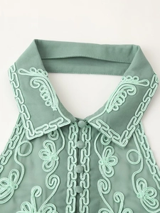 Détail d'un haut dos nu vert avec broderie vert clair et boutons recouverts de tissu
