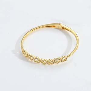 Detail of gold clover bracelet featuring sparkling heart charms set with cubic zirconia
