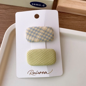 Detail of macaron plaid and green fabric hair clips on a white display card