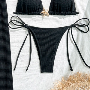 Detailed flat lay of black pleated bikini featuring a gold starfish metal ornament