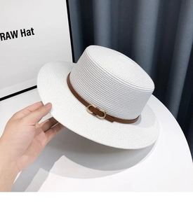 Detailed texture of white boater hat with brown leather band and gold buckle detail