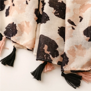 Dettaglio di sciarpa leopardata con glitter argento e nappe bicolori decorative