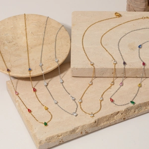 Elegant gold and silver necklaces with colorful pear-cut zircon pendants on stone