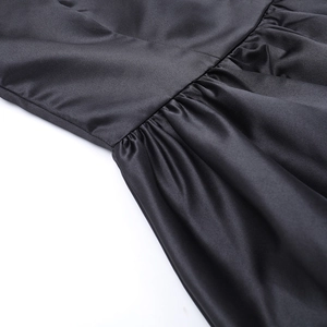 Detail shot of black satin dress showing fine pleated texture and waist seam craft