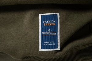 Close-up of olive green sweatshirt fabric with fashion trends woven hem label