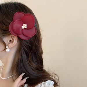 Elegant wine red fabric flower hair clip with white stamen on model side hair profile