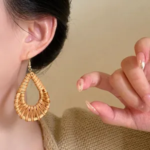 Bohemian large teardrop raffia woven earrings with gold hooks worn by a female model