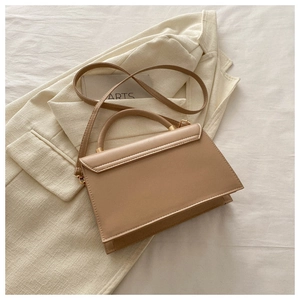 Détail du sac à main beige en similicuir avec boucles dorées et poignée arrondie