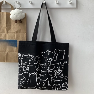 Detail of black canvas tote bag with cute white hand-drawn cat illustrations and long straps
