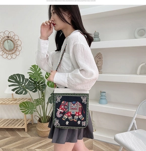 Detailed view of ethnic elephant embroidery on black canvas crossbody bag with colorful strap