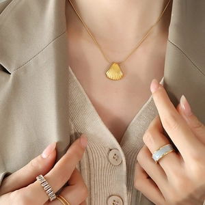 French shell pendant necklace and gold rings set for women on model in soft lighting