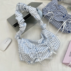 Detailed view of blue and white checkered tote bag with drawstring bows and ruffles