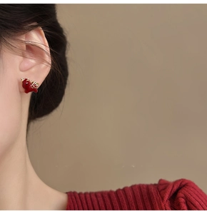 Detail of a minimalist 18k gold plated red enamel dragon stud earring on a model ear