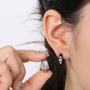 Détail de boucles d'oreilles en acier inoxydable avec trois pierres de zircone claires