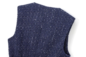 Detailed macro view of navy tweed fabric with gold sequins and textured weave pattern