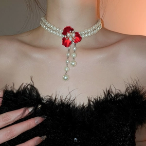 Close-up of elegant double-layered pearl necklace with a red flower and pearl tassels