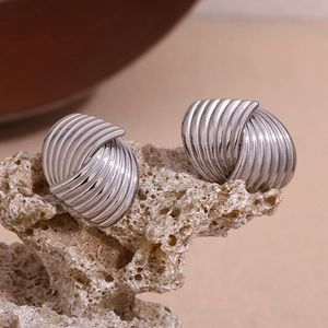 Macro shot of silver-toned textured fan-shaped earrings on a natural stone surface