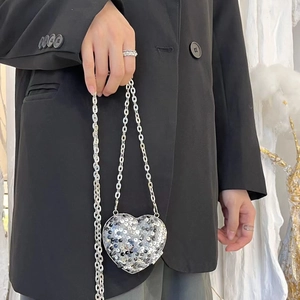 Silver heart-shaped sequin mini bag with a fine metal chain strap on a black blazer