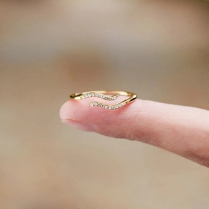 Macro shot of gold double-wave ring with pavé zircons worn elegantly on the finger