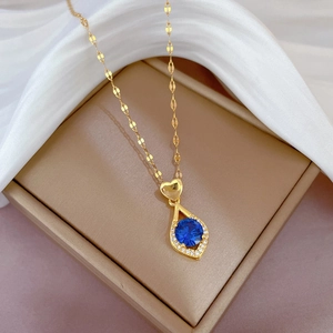 Détail d'un pendentif cœur doré avec une pierre bleue dans un écrin à bijoux
