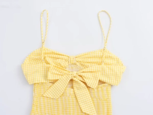 Detail of yellow gingham smocked top featuring a large bow and elastic texture