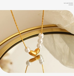 Gros plan du collier avec pendentif cœur doré et perles blanches et reflet artistique
