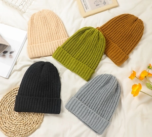 Flat lay of knit beanies in beige, green, caramel, black, and grey with soft texture