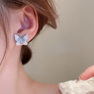 Close-up of silver butterfly stud earrings with icy gradient texture on a female model