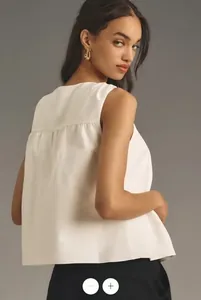 Detail view of white sleeveless top showing back pleats and minimalist A-line cut