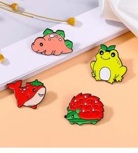 Detailed view of enamel pins featuring a pink dinosaur, yellow frog, and red hedgehog