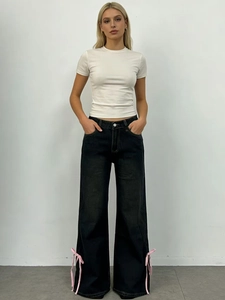 Dettaglio di fiocchi in nastro rosa sul lato dei jeans neri a gamba larga