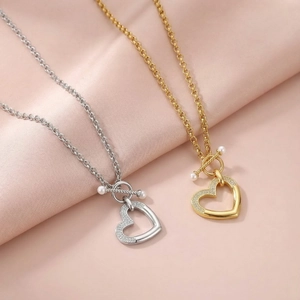 Détail de pendentifs cœur en or et argent avec strass et fermoirs à bascule en perle