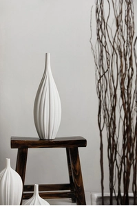 Dettaglio di un vaso in ceramica bianca con texture verticali e collo sottile moderno