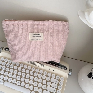 Pink corduroy makeup pouch with vintage typewriter setup and aesthetic floral decor
