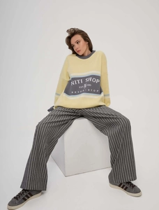 Oversize yellow knitted sweater with letter print paired with gray striped wide-leg pants