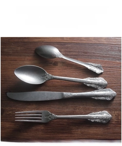 Detailed view of vintage embossed handles on matte stainless steel cutlery set