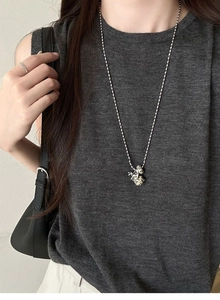 Detailed view of a silver long necklace with a cute black and white spotted puppy pendant
