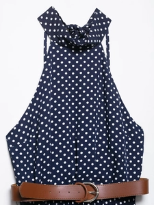 Close-up of navy blue polka dot halter dress featuring a matching brown waist belt