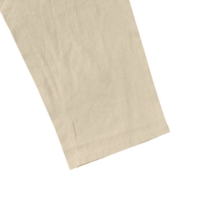 Detailed close-up of the fine stitching and natural linen texture of a beige men's beach set