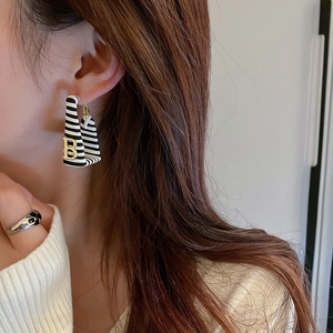 Close-up of square striped faux leather earrings featuring a gold letter B metal charm