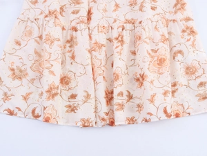 Dettaglio dell'orlo in chiffon bohémien con motivo floreale arancione e marrone