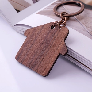 Custom house-shaped wooden keychain with retro bronze ring on white book edge