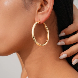 Close-up of model wearing large oversized golden hoop earrings with polished finish