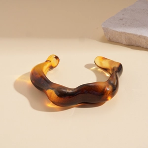 Macro detail of amber acrylic wave bracelet with translucent tortoiseshell texture